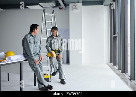 Builders in grey uniform talking after finishing work in building after construction Stock Photo