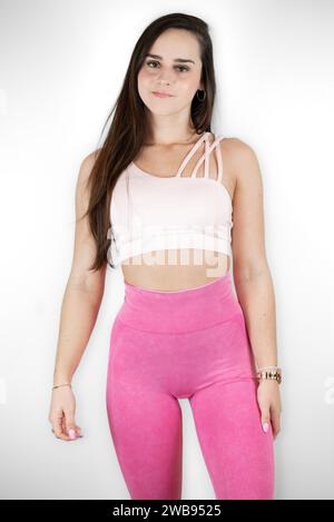 A young female adult stands against a plain white background, posing for a photograph Stock Photo