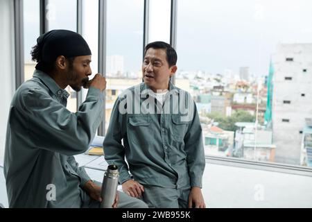 Builders drinking hot coffee from thermos when having break at work Stock Photo