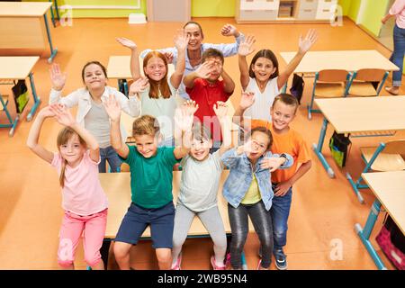 High angle view of happy male and female students waving with teacher in classroom at school Stock Photo