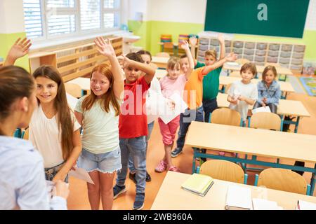 High angle view of diverse happy students waving at teacher while standing in row in classroom Stock Photo