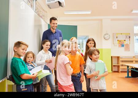 Smiling male teacher standing with group of school students in classroom Stock Photo