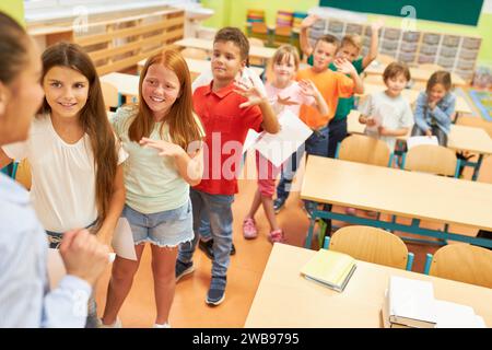 High angle view of diverse schoolkids waving at female teacher in classroom Stock Photo