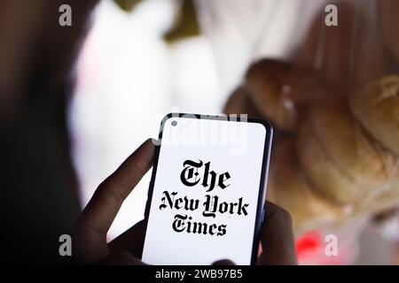 Dhaka, Bangladesh - 09 January 2024: Hands holding a smartphone with The New York Times logo on the screen. The New York Times is an American newspaper. Stock Photo