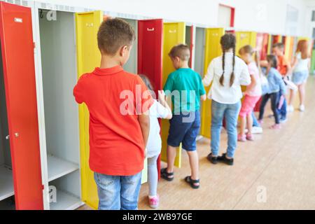 Group of male and female students standing near lockers in hallway at school Stock Photo