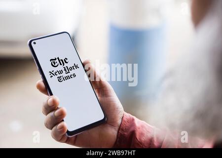 Dhaka, Bangladesh - 09 January 2024: Hands holding a smartphone with The New York Times logo on the screen. The New York Times is an American newspaper. Stock Photo