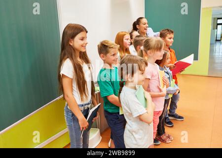 Group of smiling male and female students standing together holding books in classroom Stock Photo