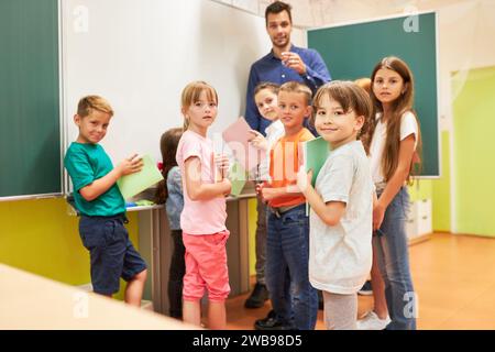 Portrait of diverse school children holding books while standing in classroom Stock Photo