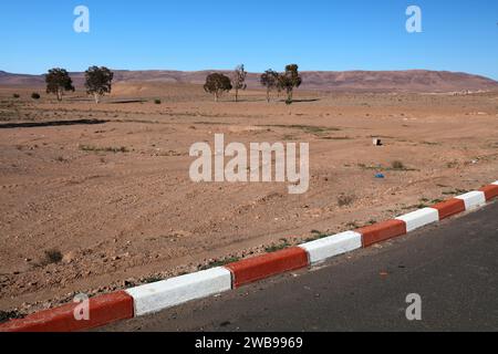 Red white curb paint marking in a desert in Morocco. No parking marking. Stock Photo