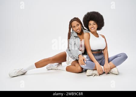 beautiful young african american women sitting together on grey background, Juneteenth concept Stock Photo