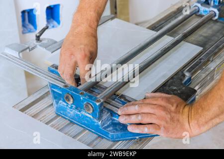 Using tile cutting hand machine, construction worker cuts ceramic tile. Stock Photo
