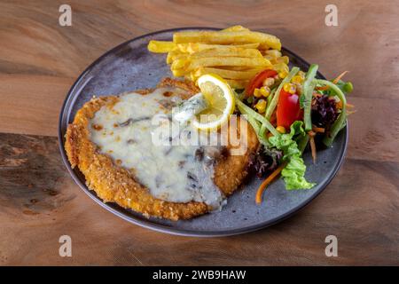 Chicken schnitzel in sauce with potato wedges. Wooden table. Top view Stock Photo
