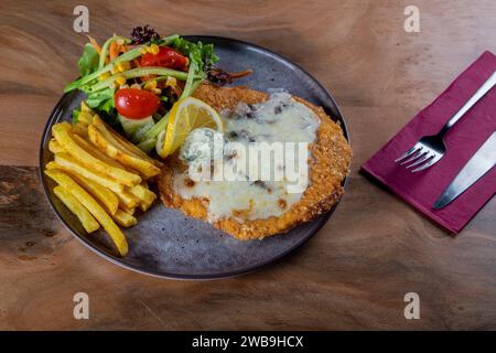 Chicken schnitzel in sauce with potato wedges. Wooden table. Top view Stock Photo