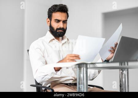 Focused professional indian businessman examining documents at his desk Stock Photo