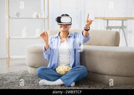 Excited asian woman using VR headset at home, watching movie Stock Photo