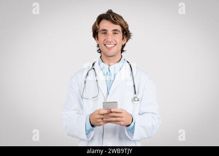 Smiling doctor using smartphone for healthcare apps Stock Photo
