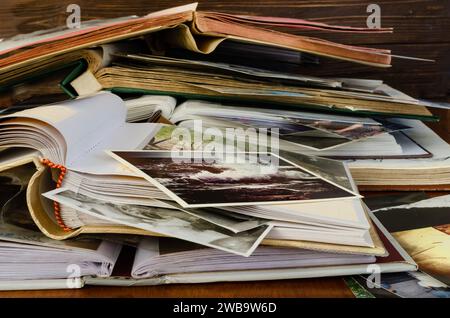 Nostalgia - old family photo albums and photos lie a heap on a wooden table. Stock Photo