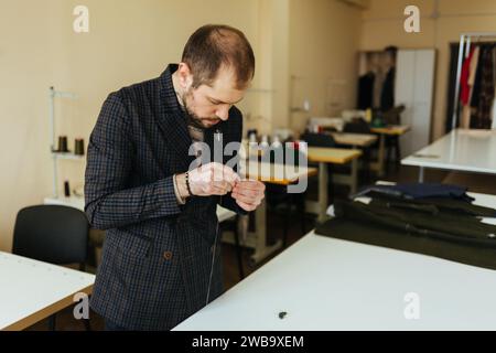 Tailor cutting wool fabric. the line pattern. Craftsman Makes rectangular blanks for Bow ties of woolen fabric. Work with sewing machine in a textile Stock Photo