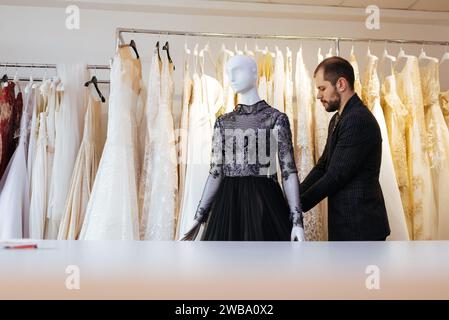 Young man putting clothes on a mannequin in store. Stock Photo
