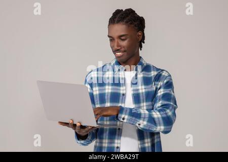 Freelance Work. Portrait Of Smiling African American Guy Using Laptop Stock Photo