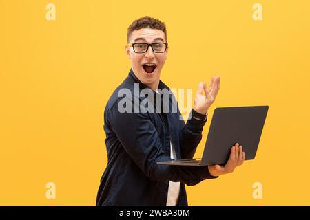 Amazed young man in eyeglasses using laptop computer Stock Photo