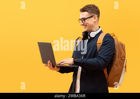 Cool young guy student with backpack using laptop Stock Photo
