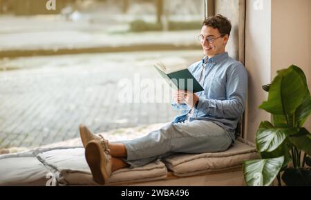 Focused calm smart european young man student in glasses read book, enjoy peace Stock Photo