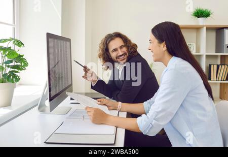 Two colleagues working with spreadsheets together, making funny jokes and laughing Stock Photo