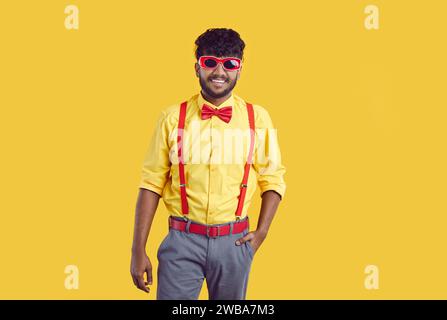 Young happy smiling indian guy in funny party outfit and sunglasses in studio. Stock Photo