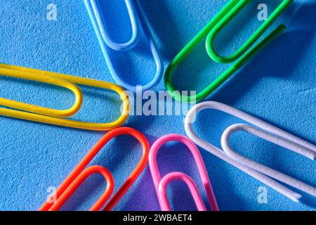 Multi colored paper clips are folded in shape star blue background Stock Photo