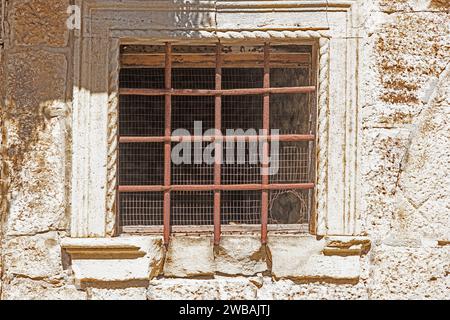 Picture of an old barred window with rusty bars in the sunlight during the day Stock Photo