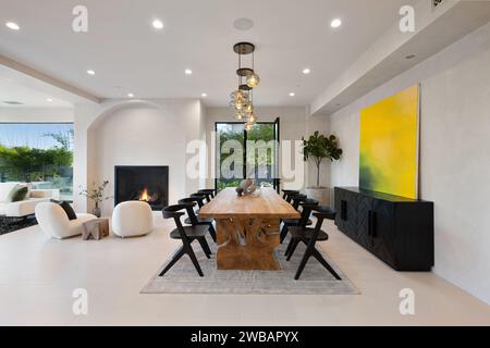 A spacious dining room with a long wooden table and six chairs surrounding it, perfect for hosting a family dinner or a gathering with friends Stock Photo