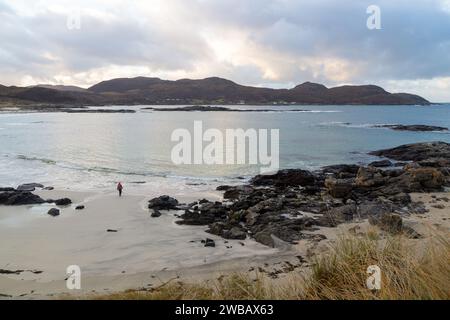 Walking on Sanna Bay on the Ardnamurchan Peninsula with the village of Portuairk in the background, Lochaber, Highland, Scotland Stock Photo