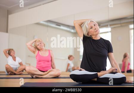 Mature woman making stretching exercises in fitness studio Stock Photo