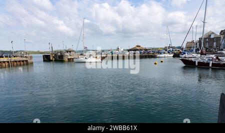 Yacht leaving Padstow harbour entrance with boat leaving at high water Stock Photo