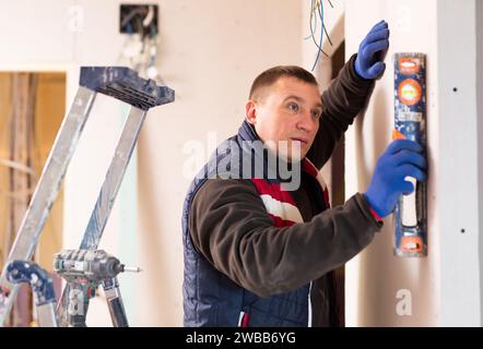 Builder checks the vertical of the wall using level Stock Photo