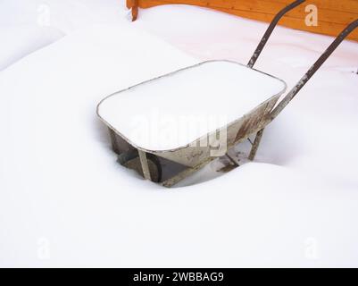 Wheelbarrow covered with snow in the snowdrift in winter Stock Photo