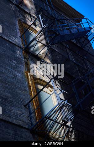 Urban Fire Escape Geometric Shadows on Brick Facade Stock Photo