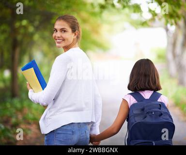 Happy woman, teacher and walking student to school in park or outdoor forest for support or responsibility. Female person, educator smile and holding Stock Photo