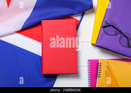 Learning foreign language. Flag of United Kingdom, books, stationary and glasses on white table, flat lay Stock Photo