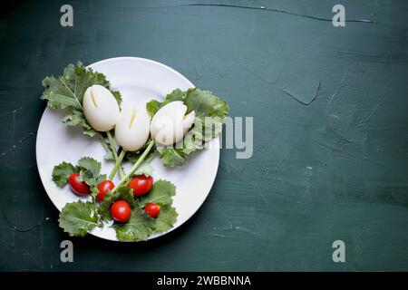 Fun, colorful creative boiled egg tulip flowers for children with cherry tomatoes for Easter eggs and kale for leaves to encourage kids to eat healthy Stock Photo