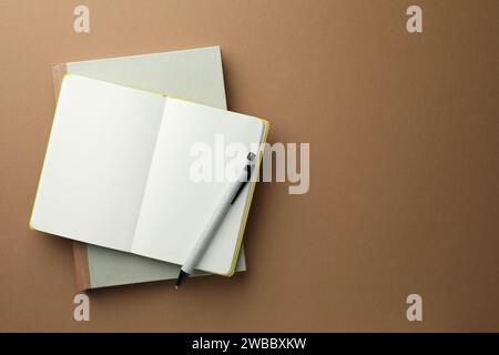 Notebooks and pen on light brown background, top view. Space for text Stock Photo