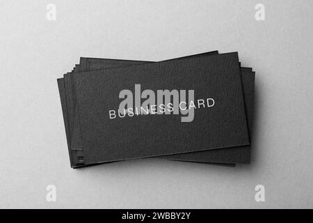 Stack of business cards with text on grey background, top view Stock Photo