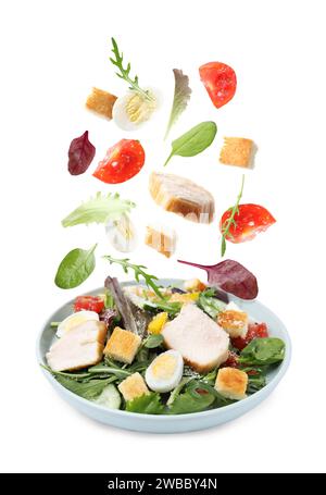 Ingredients falling into plate with tasty salad on white background Stock Photo