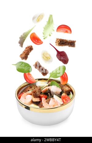 Ingredients falling into bowl with tasty salad on white background Stock Photo