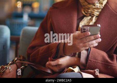 young women hand holding smart phone sitting on cafe sofa  Stock Photo