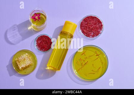 Concept for cosmetic advertisement with saffron extract and honey. On a purple background, fresh ingredients in petri dishes and unlabeled cosmetic bo Stock Photo