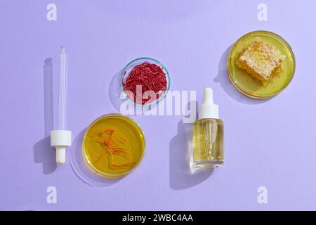 Scene for cosmetic serum advertisement with expensive ingredients like saffron and honey on purple background. Saffron, a spice that originated in Asi Stock Photo