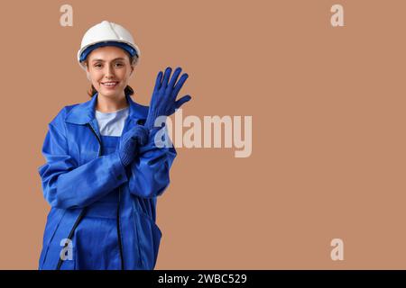 Female worker putting gloves on brown background Stock Photo