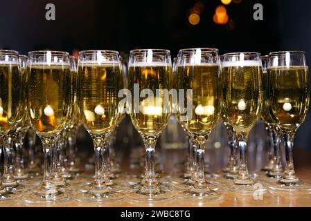 Rows of filled champagne flutes, beautifully lined up on a wooden table, ready for a celebratory toast. Stock Photo